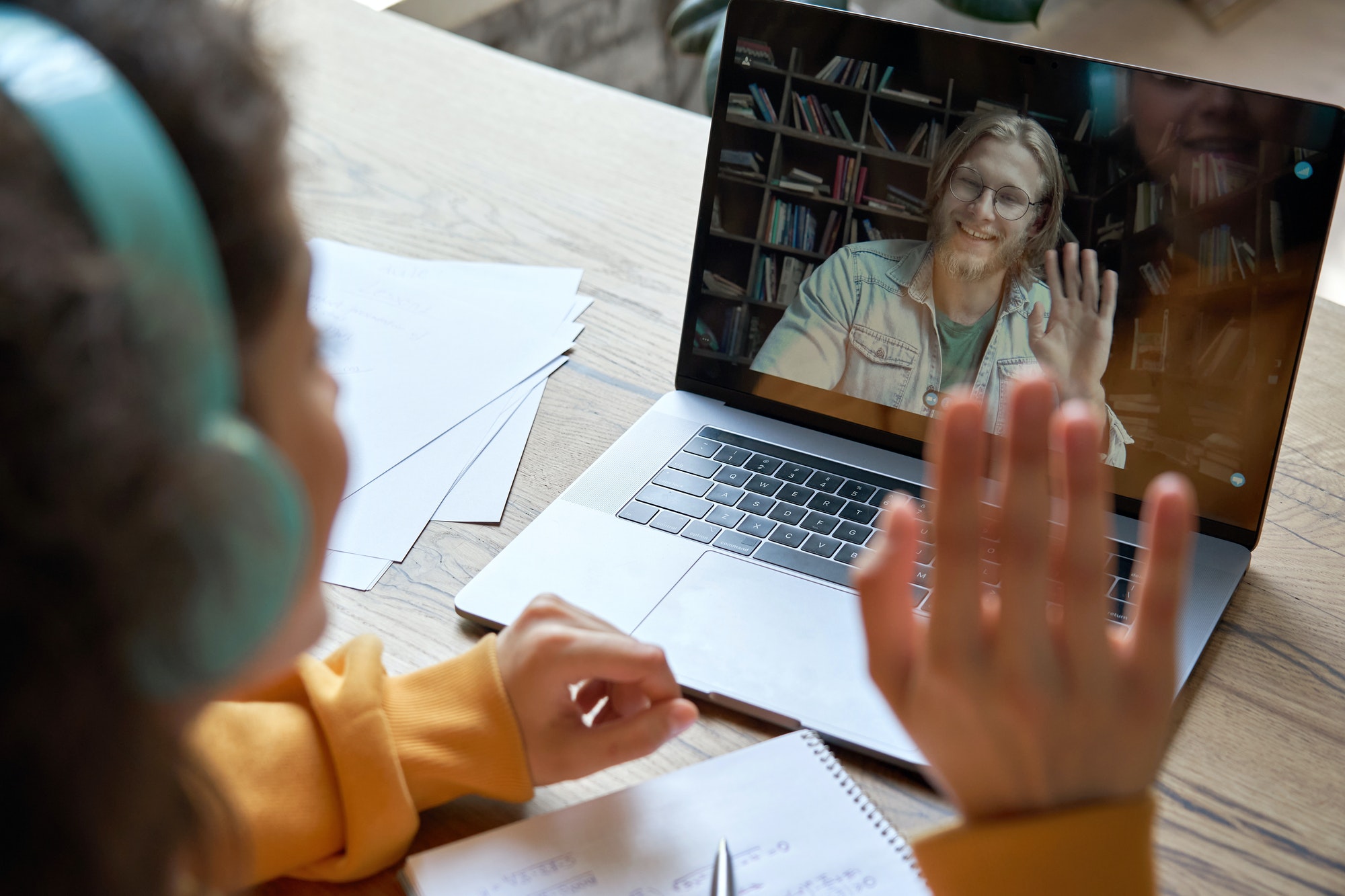 Hispanic teen girl distance learning with online teacher on laptop screen.